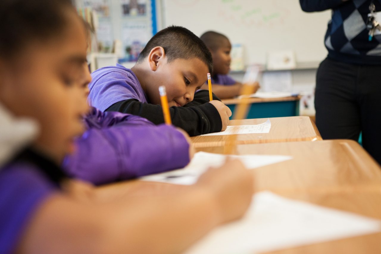 Aspire Student writing at his desk with a pencil